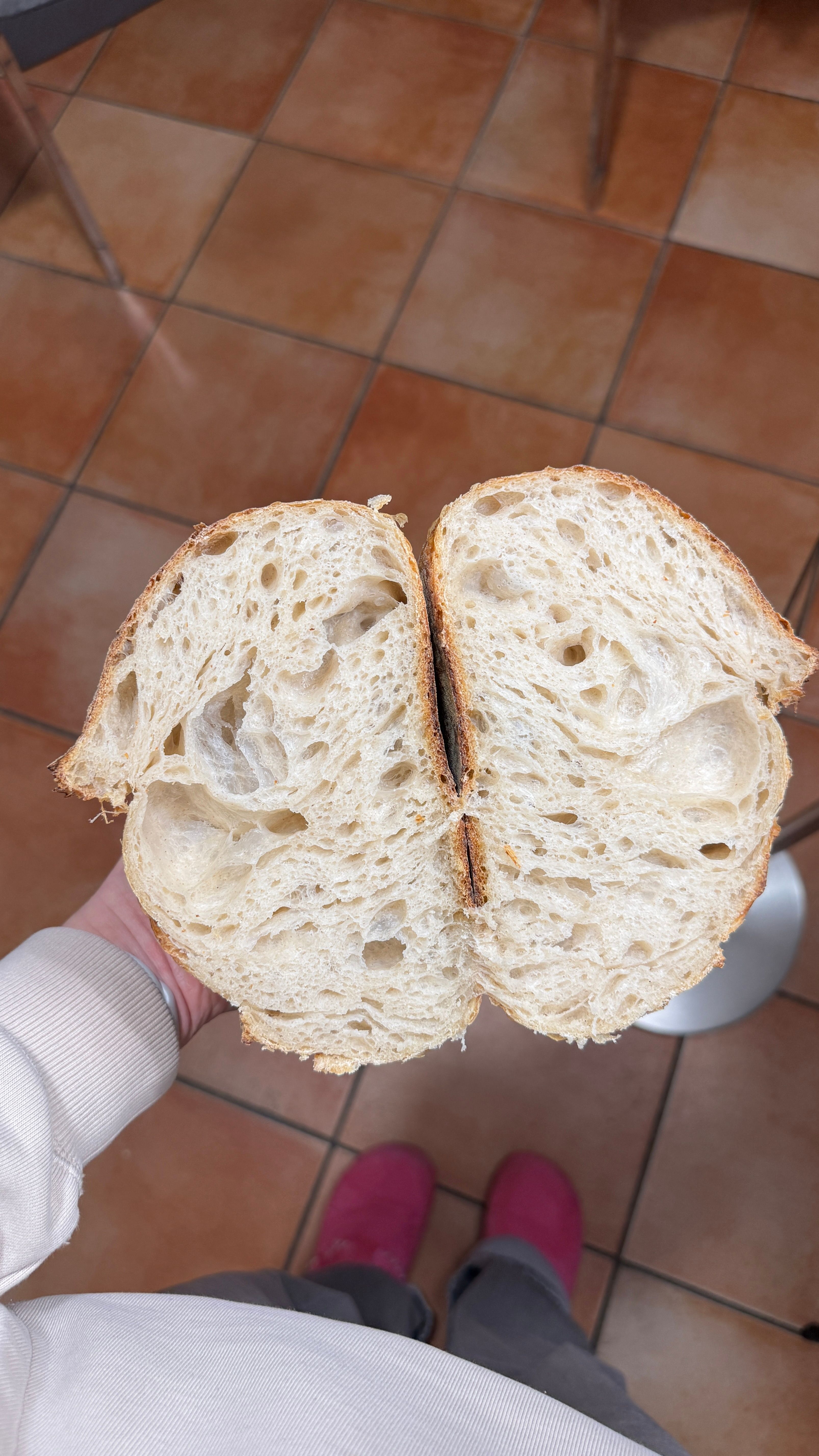 Sliced sourdough bread recipe beginner loaf on wooden board, showing open crumb and golden crispy crust