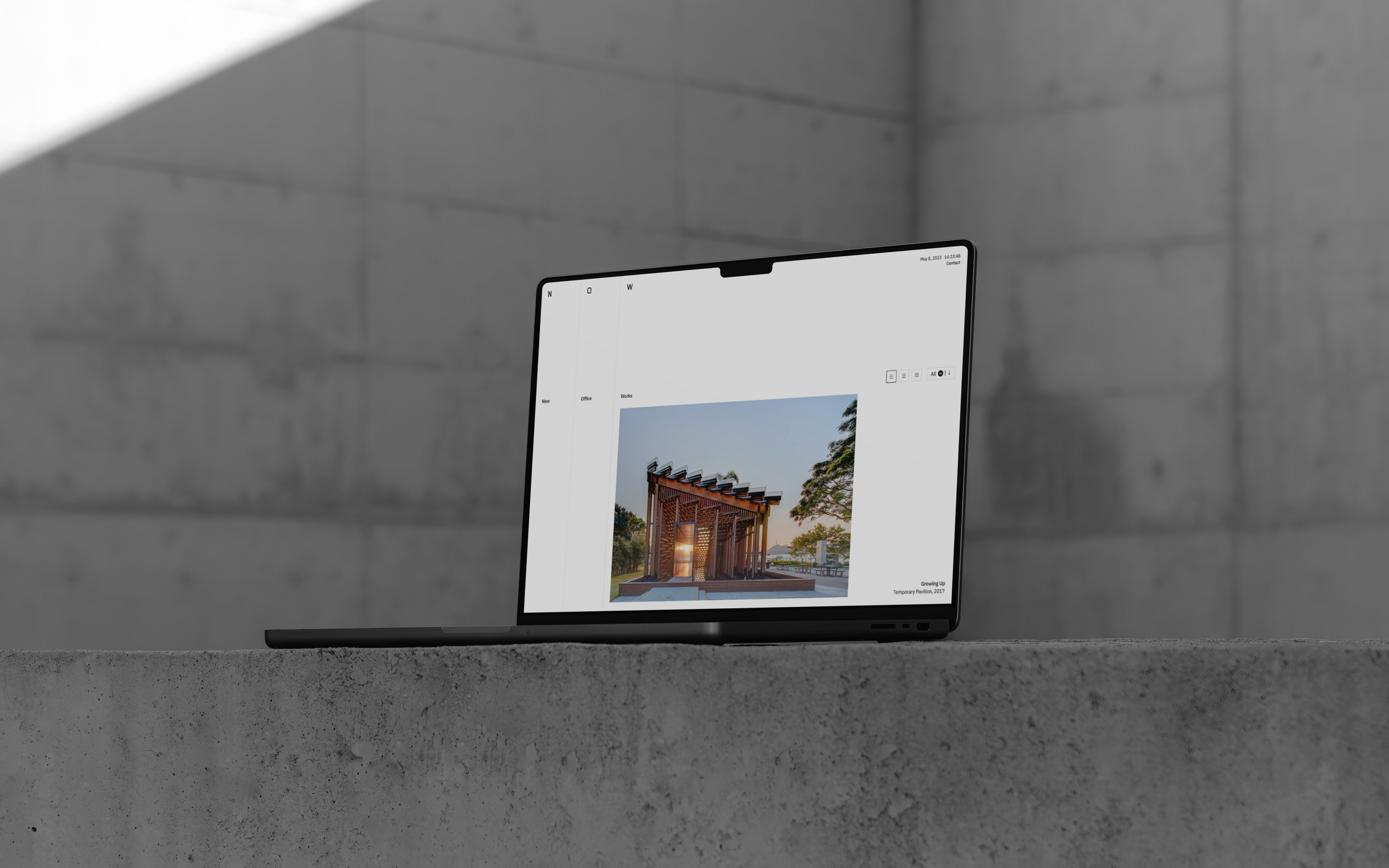 A laptop sat on a concrete block displaying the website of New Office Works