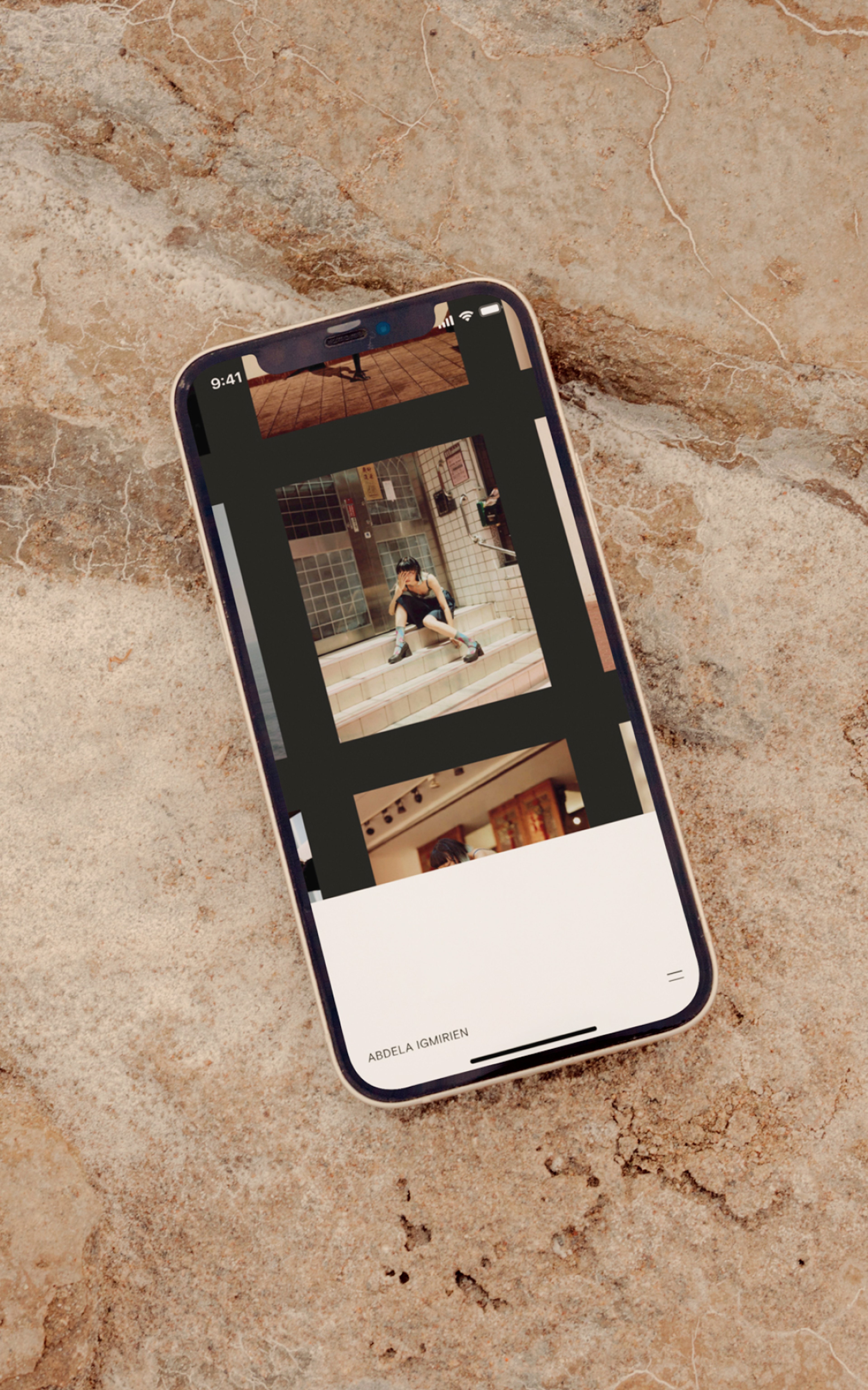 iPhone laying on a marble surface displaying the Abdela Igmirien portfolio project