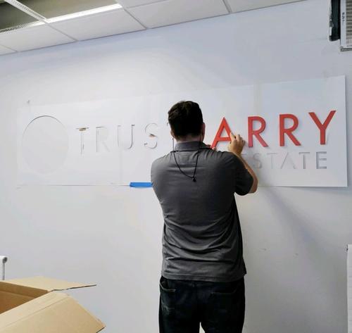 Man putting up "Trust Larry" signage on office wall