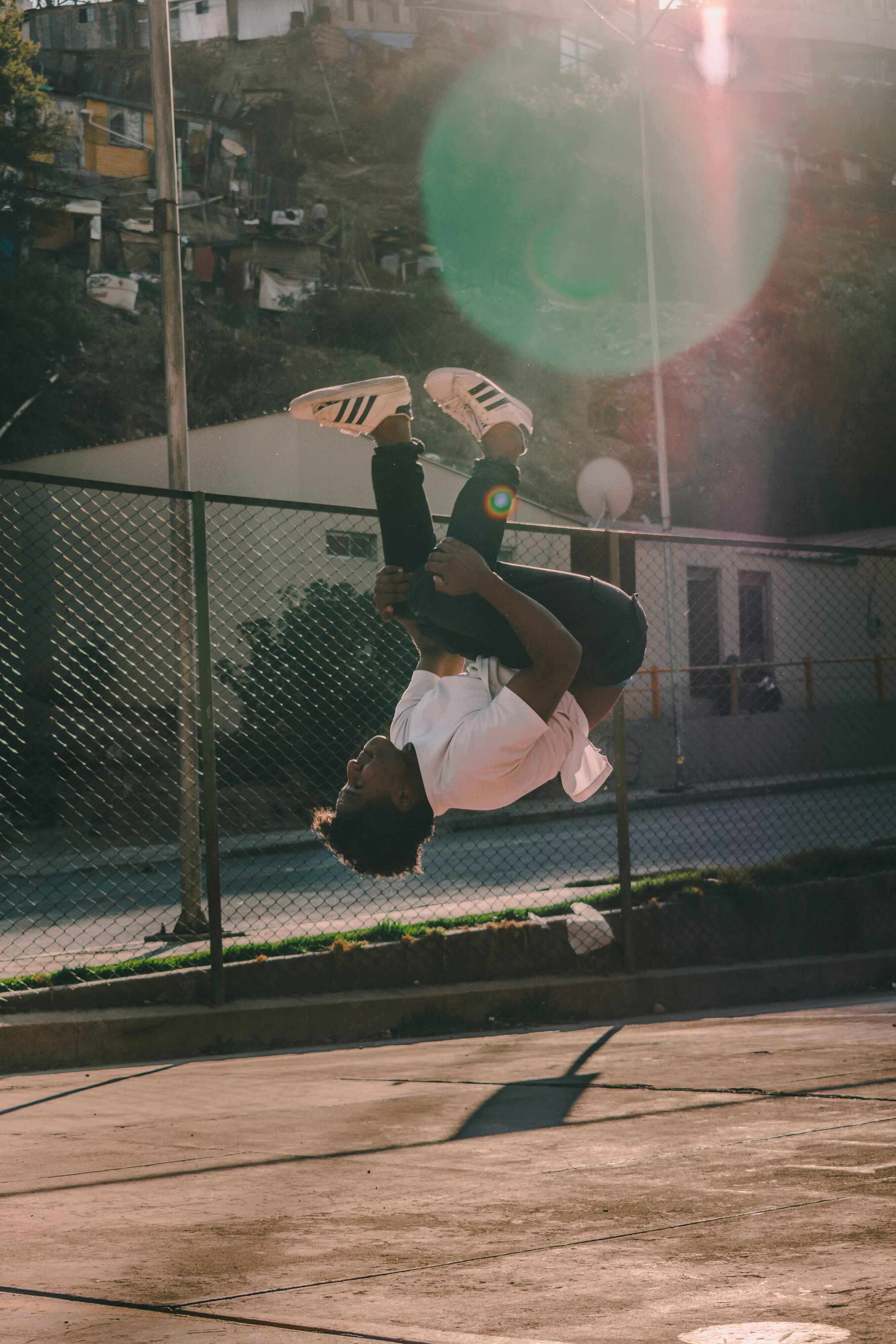 A boy performing a backflip in an outdoor court.