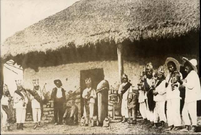 Danzantes y músicos frente a una casa de techo de palma en Yahualica, fotografiados en 1890