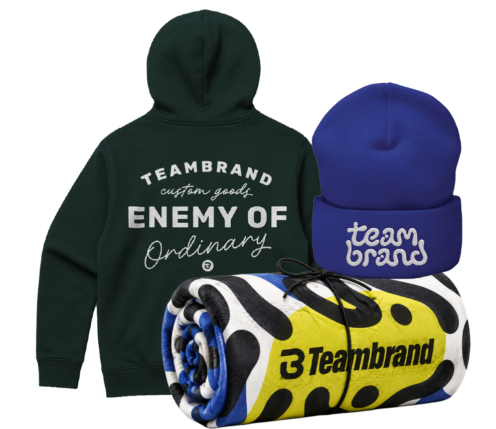 TeamBrand branded hoodie, beanie, and rolled blanket arranged together as a gear drop package.
