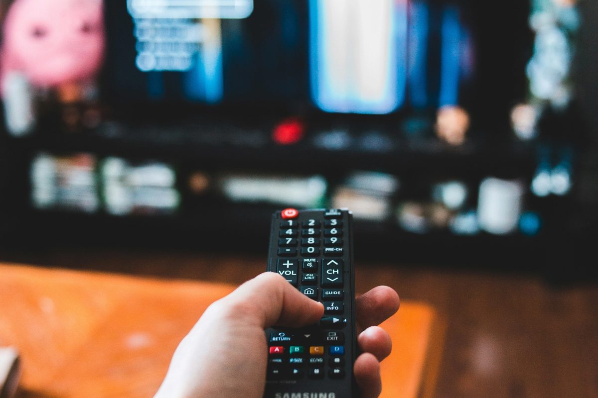 Person holding a remote control with the television in the foreground