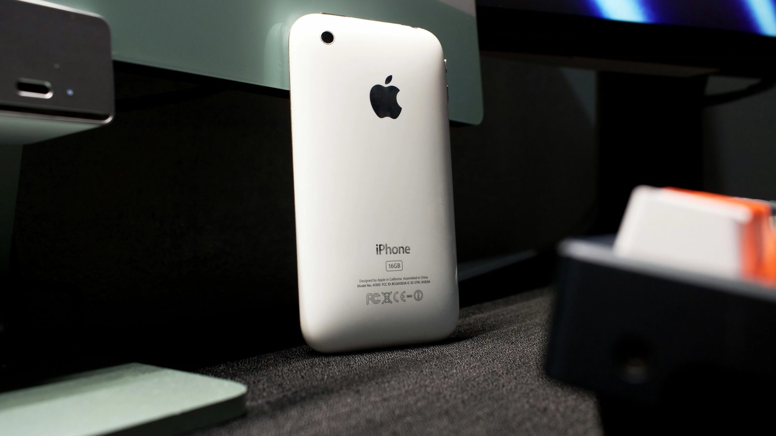 A white iphone sitting on top of a desk next to a monitor