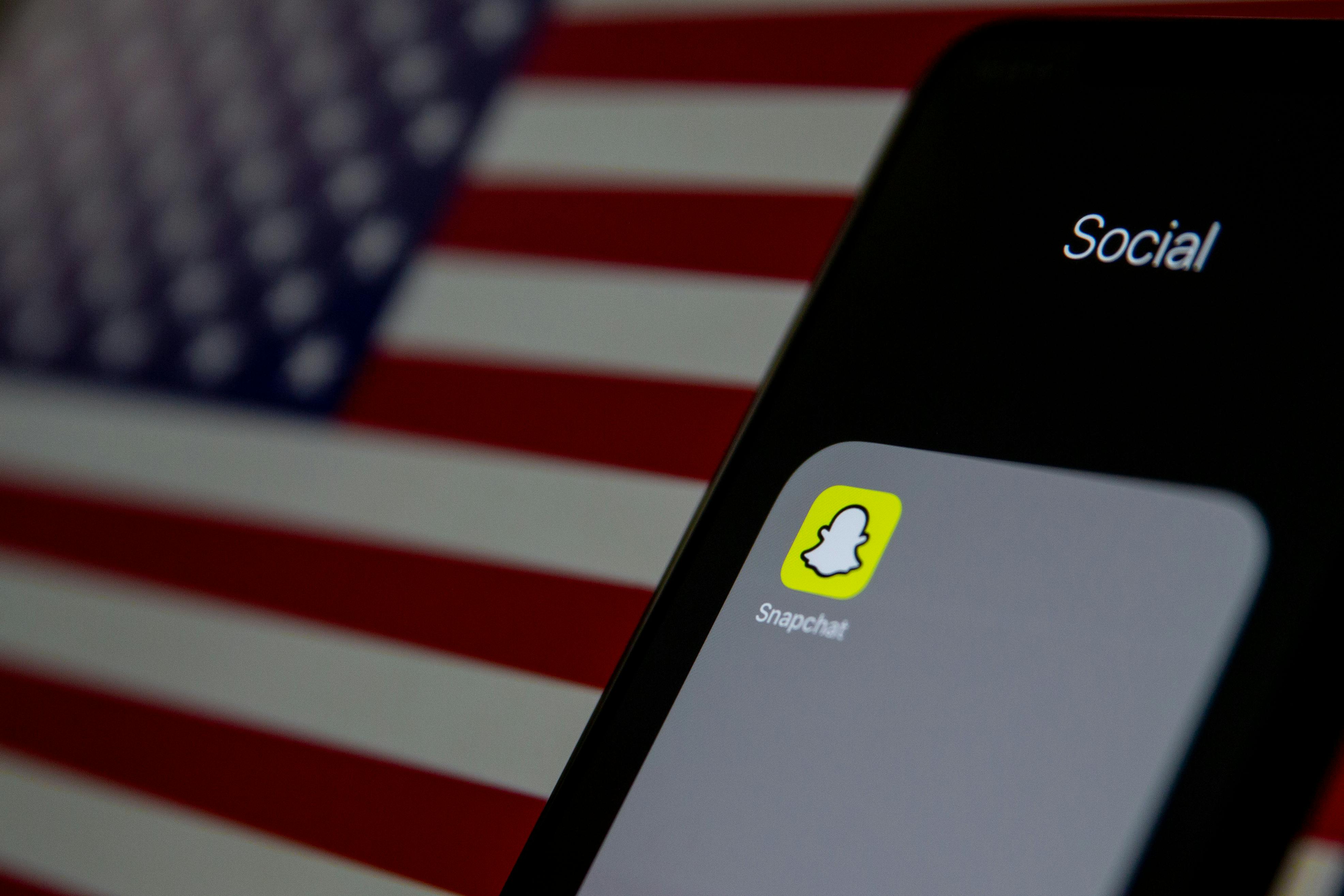 Snapchat app on mobile phone with American flag as a backdrop