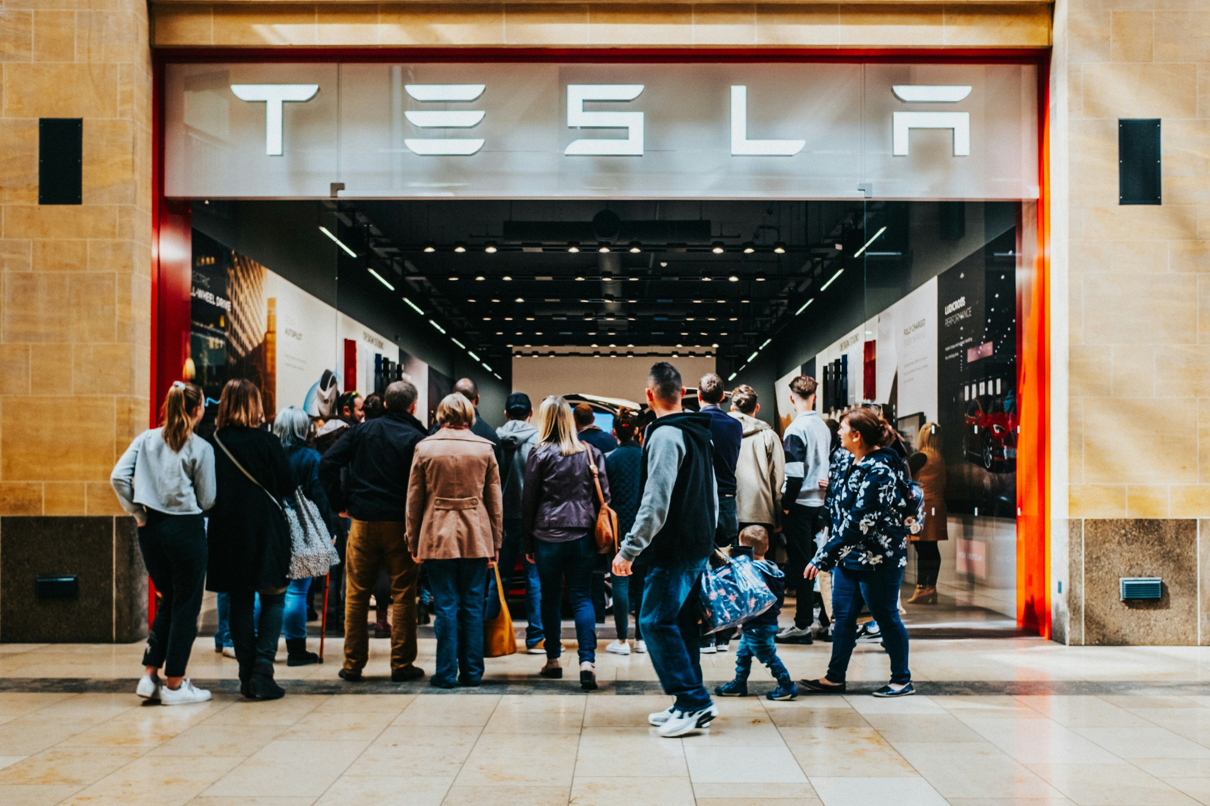 Shopping crowd around a Tesla store.