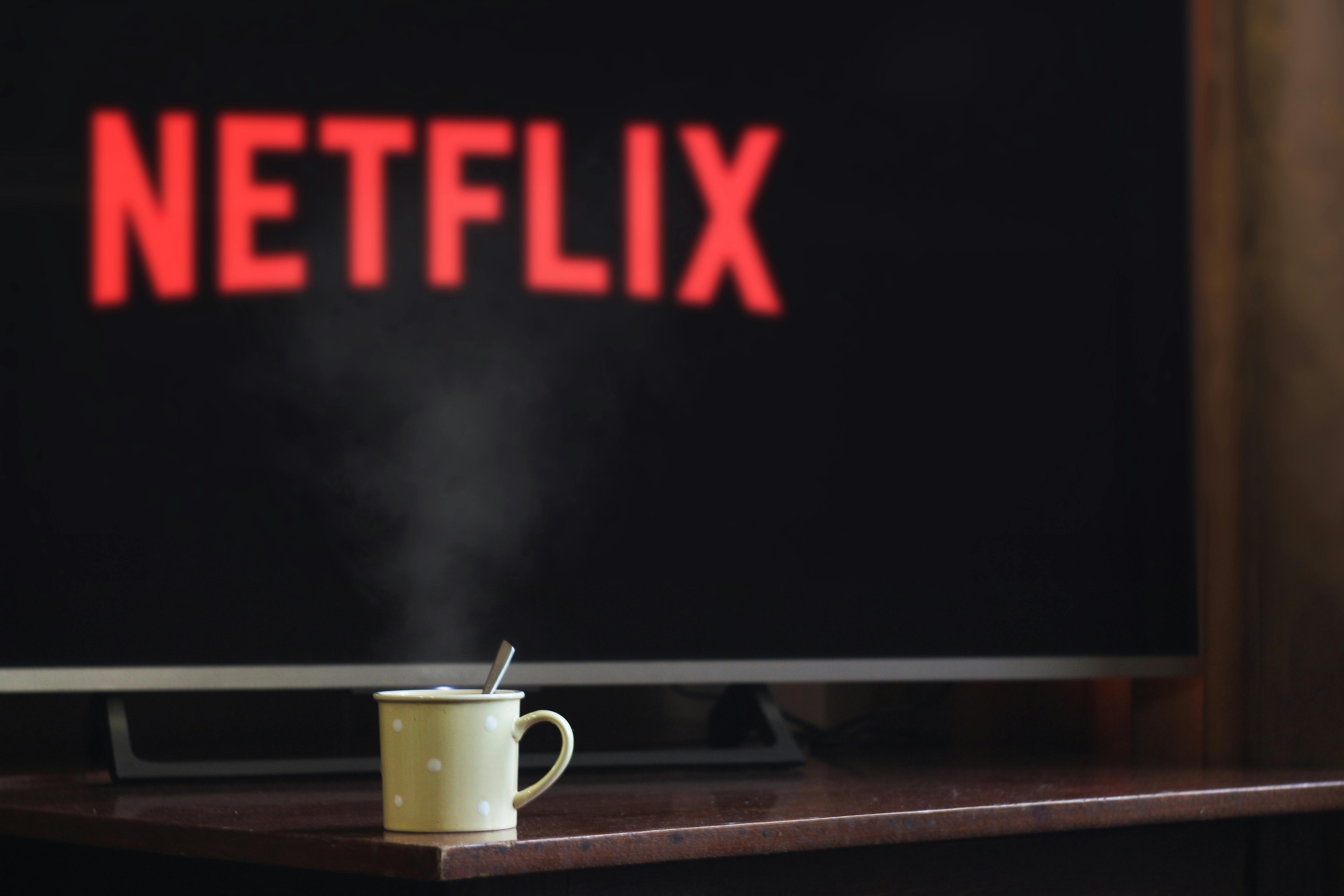 Cup of coffee in the foreground with Netflix in the background on TV