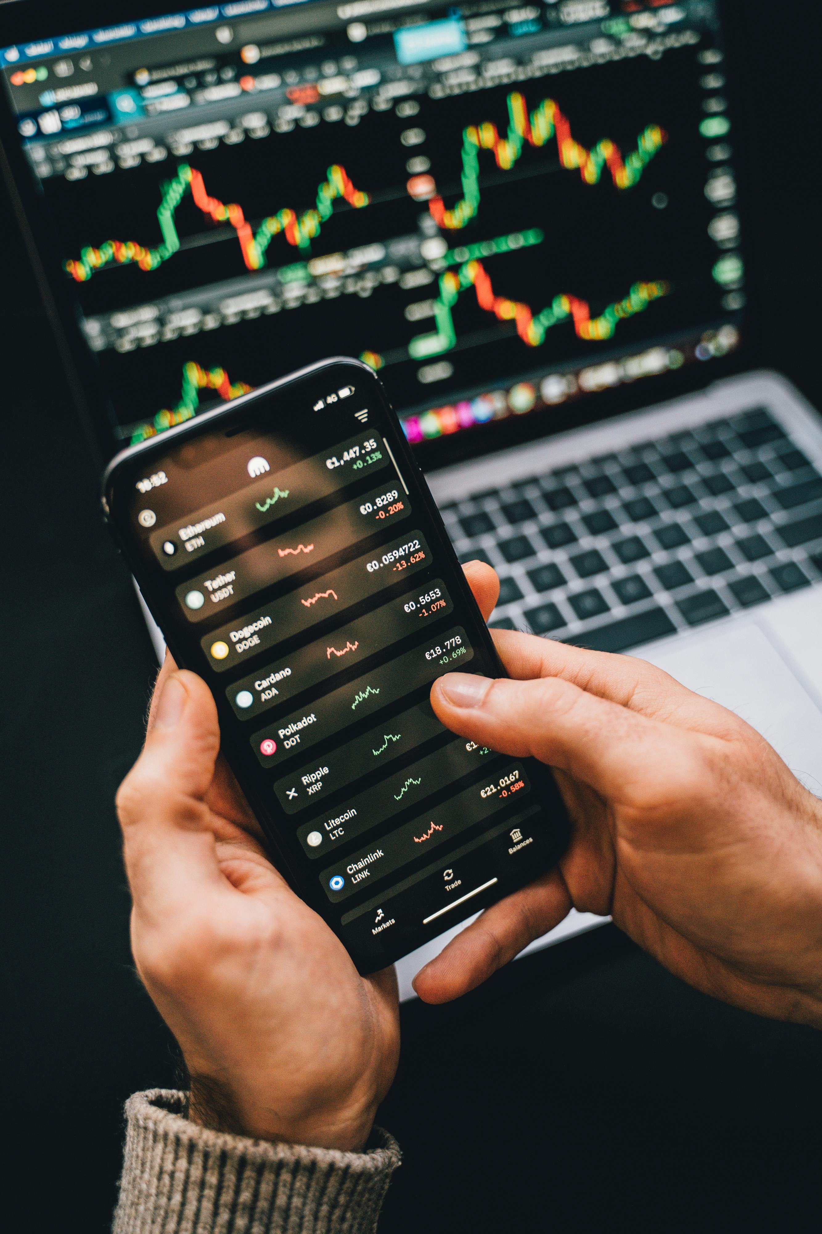 Main Image: Man holding Iphone watching stocks