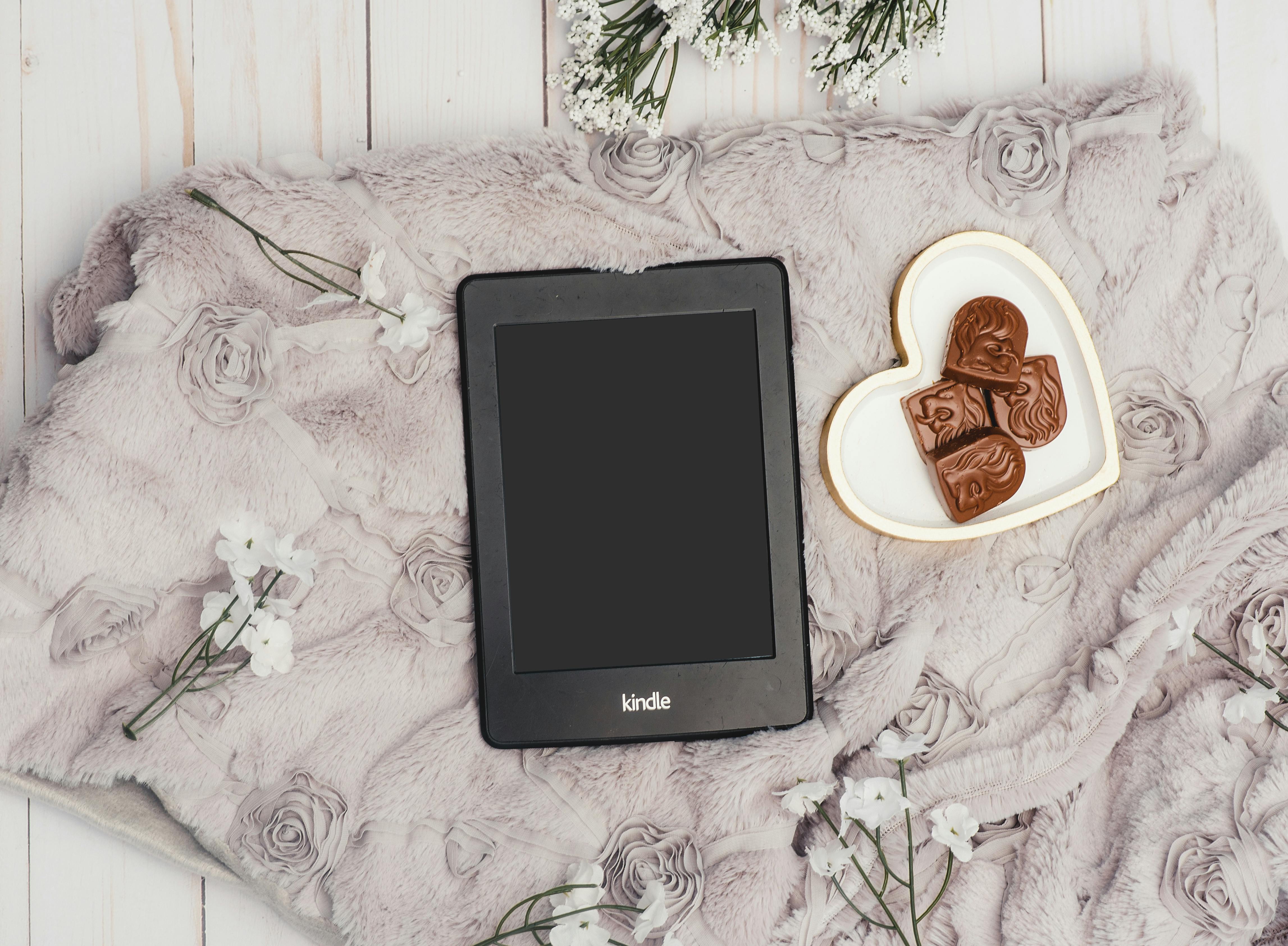 Black Amazon Kindle next to a bowl of chocolates