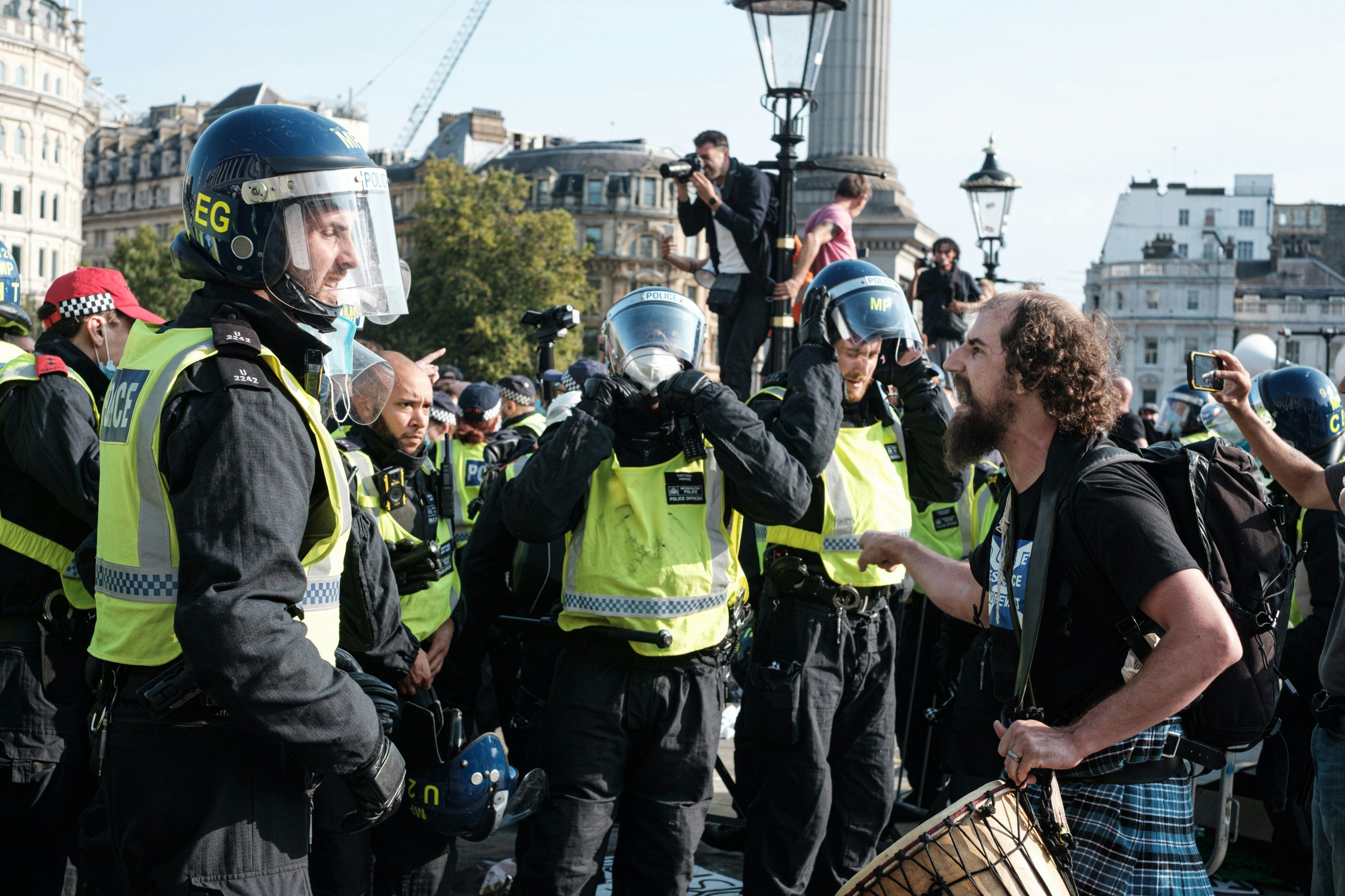 Main Image: A protestor faces anti-riot police in Trafalgar Square, London