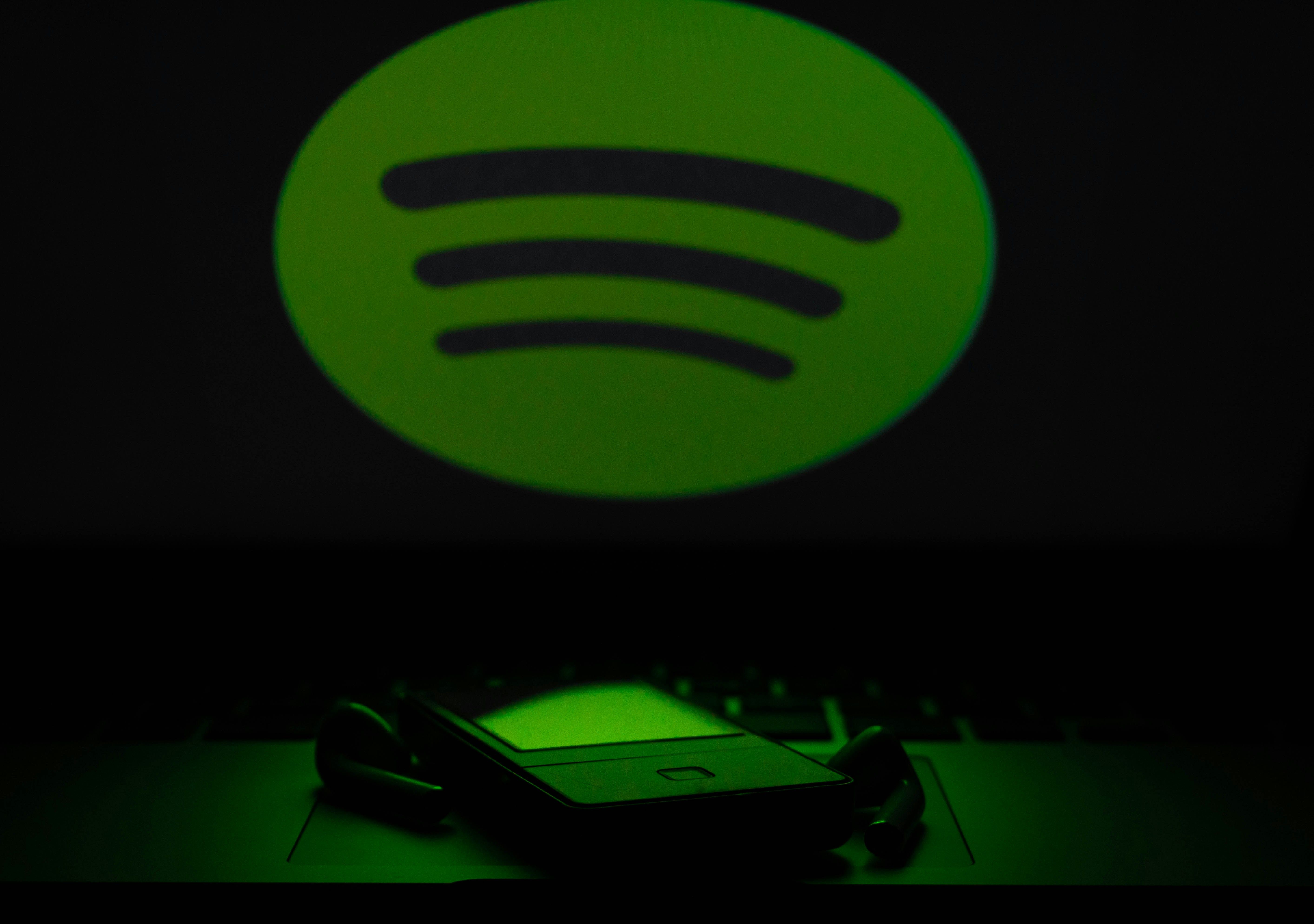 Phone using Spotify app, with a Spotify logo in the foreground