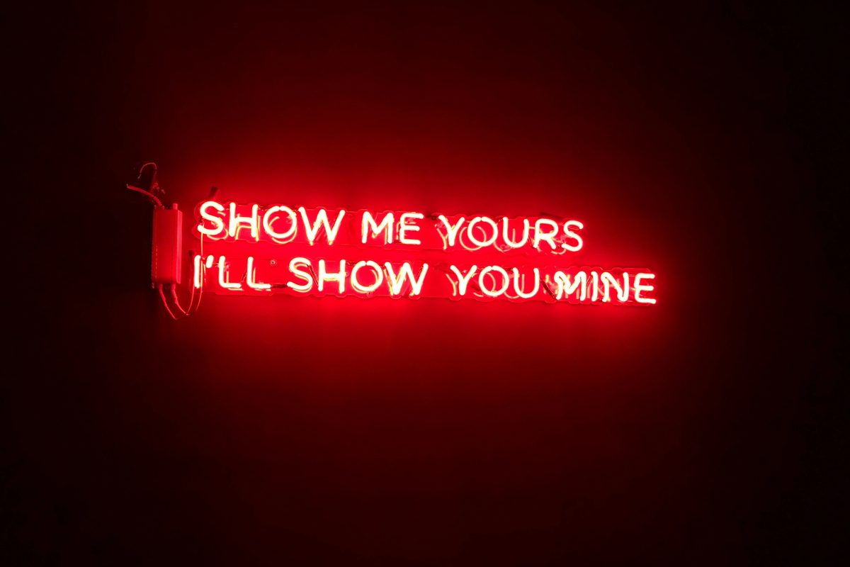 NSFW neon sign that reads "Show me yours I'll show you mine."
