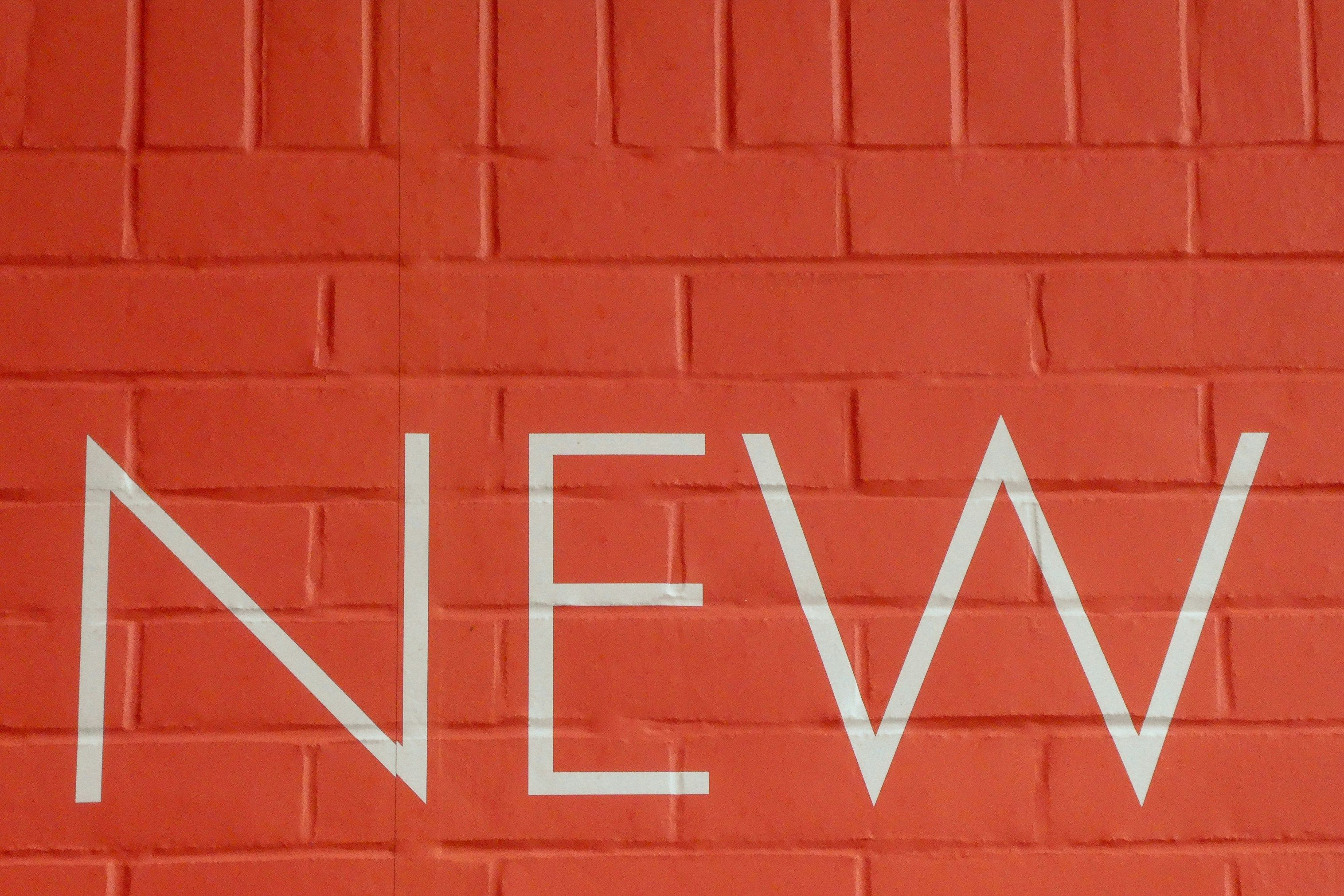 Word 'New' written on a red wall