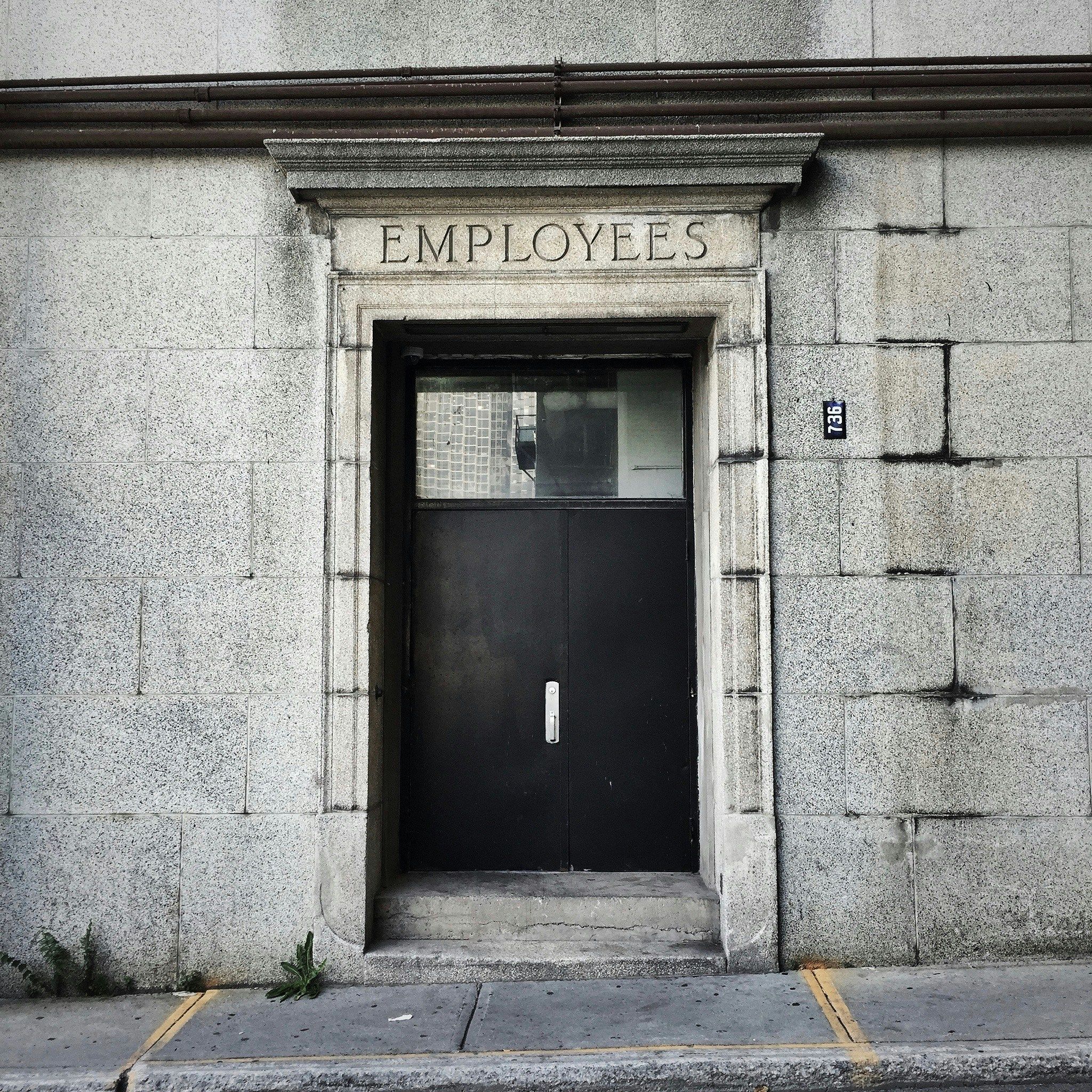 Black wooden door written "Employees"