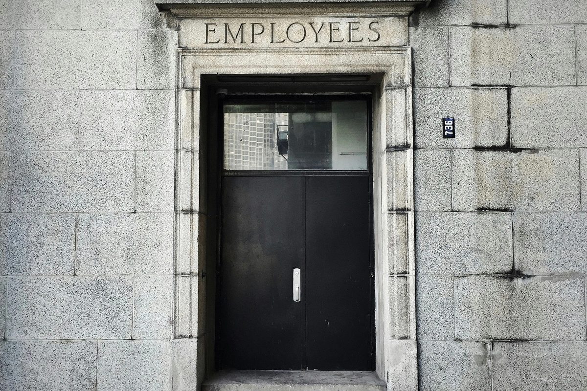 Black wooden door written "Employees"