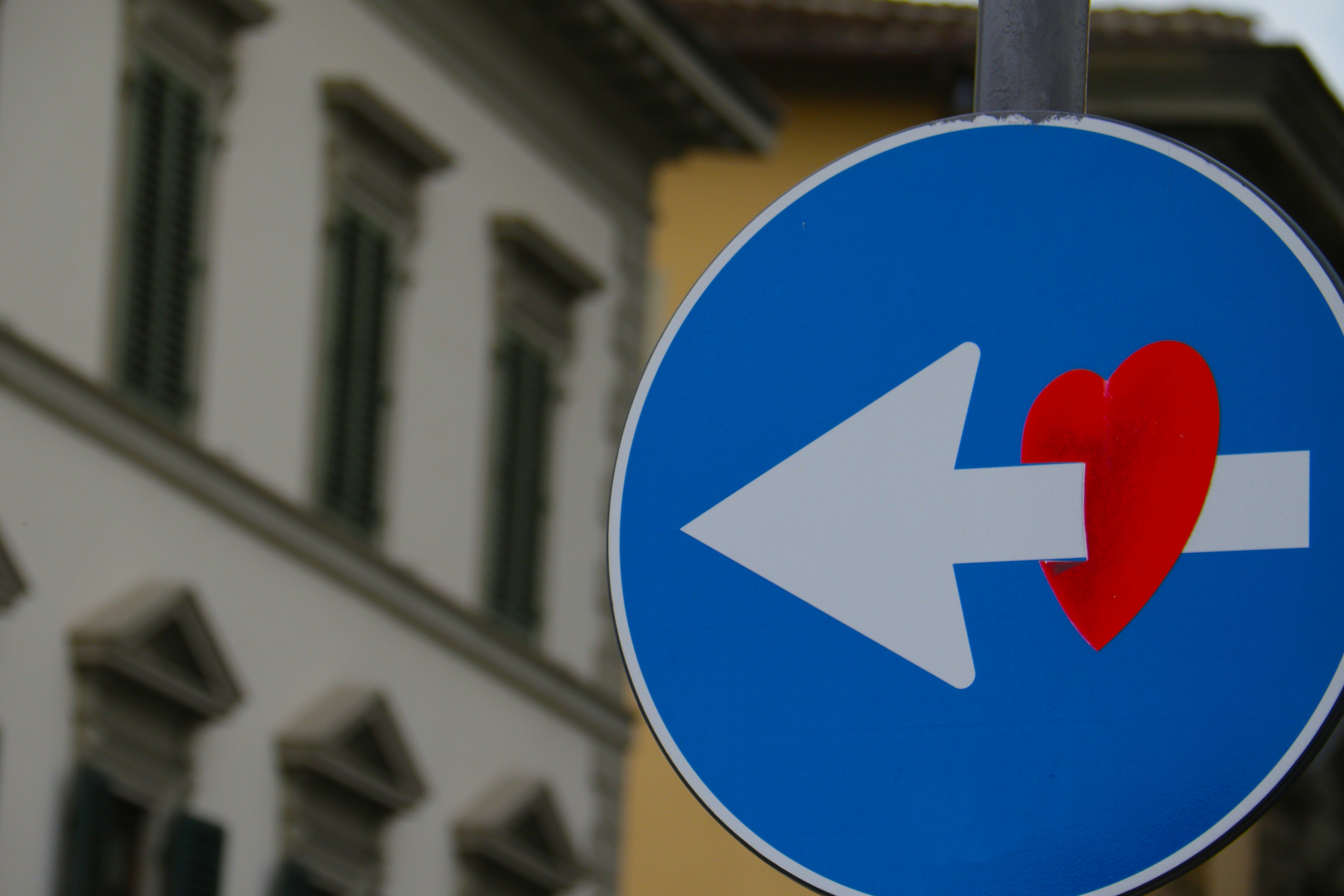 A white arrow through a red heart road signage