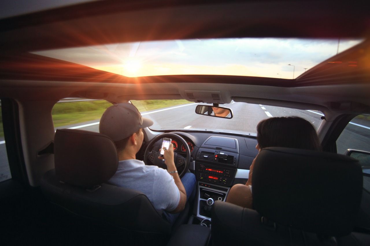 A man driving while using their phone