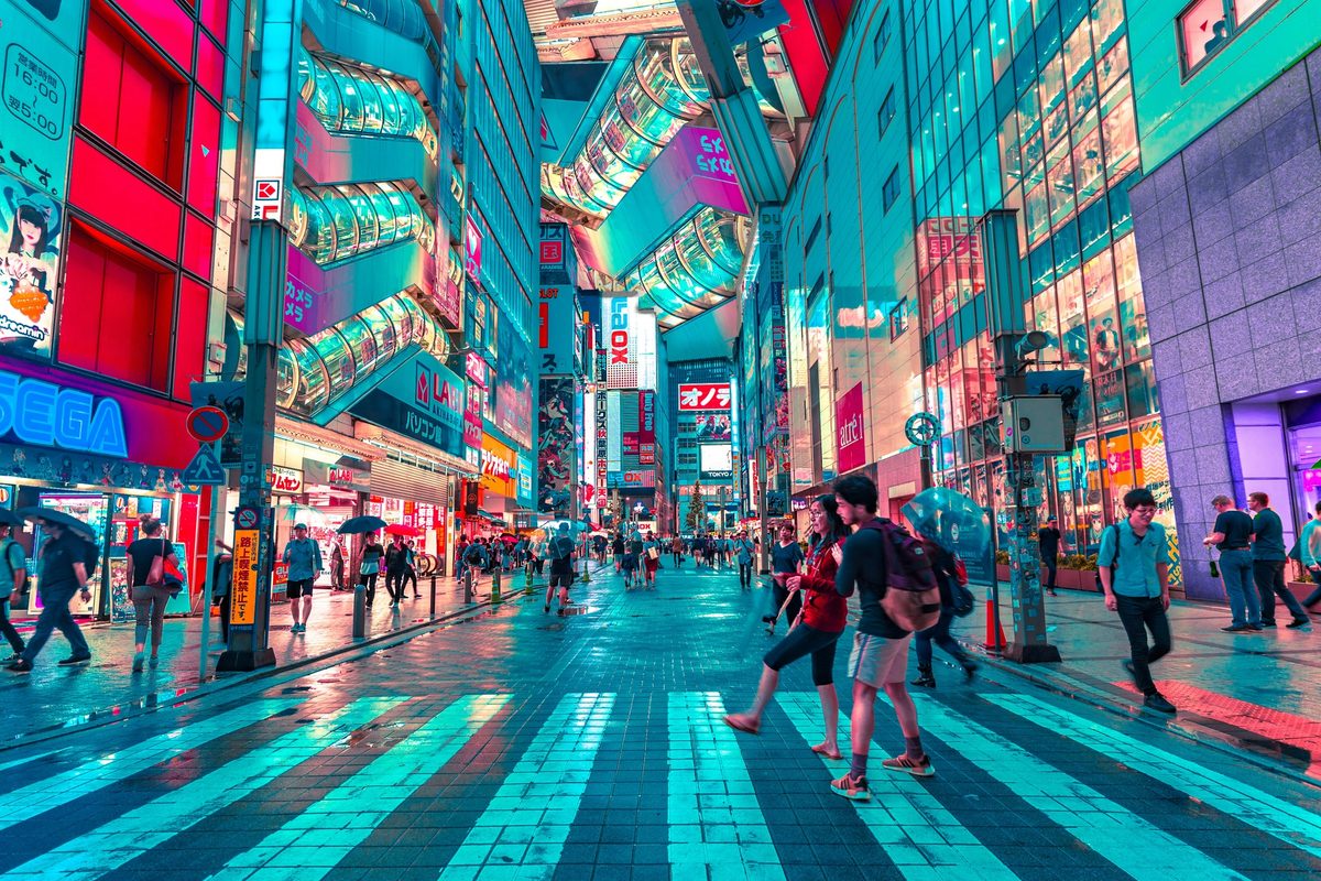 People walking on a road in Tokyo with well-lit buildings in the backdrop