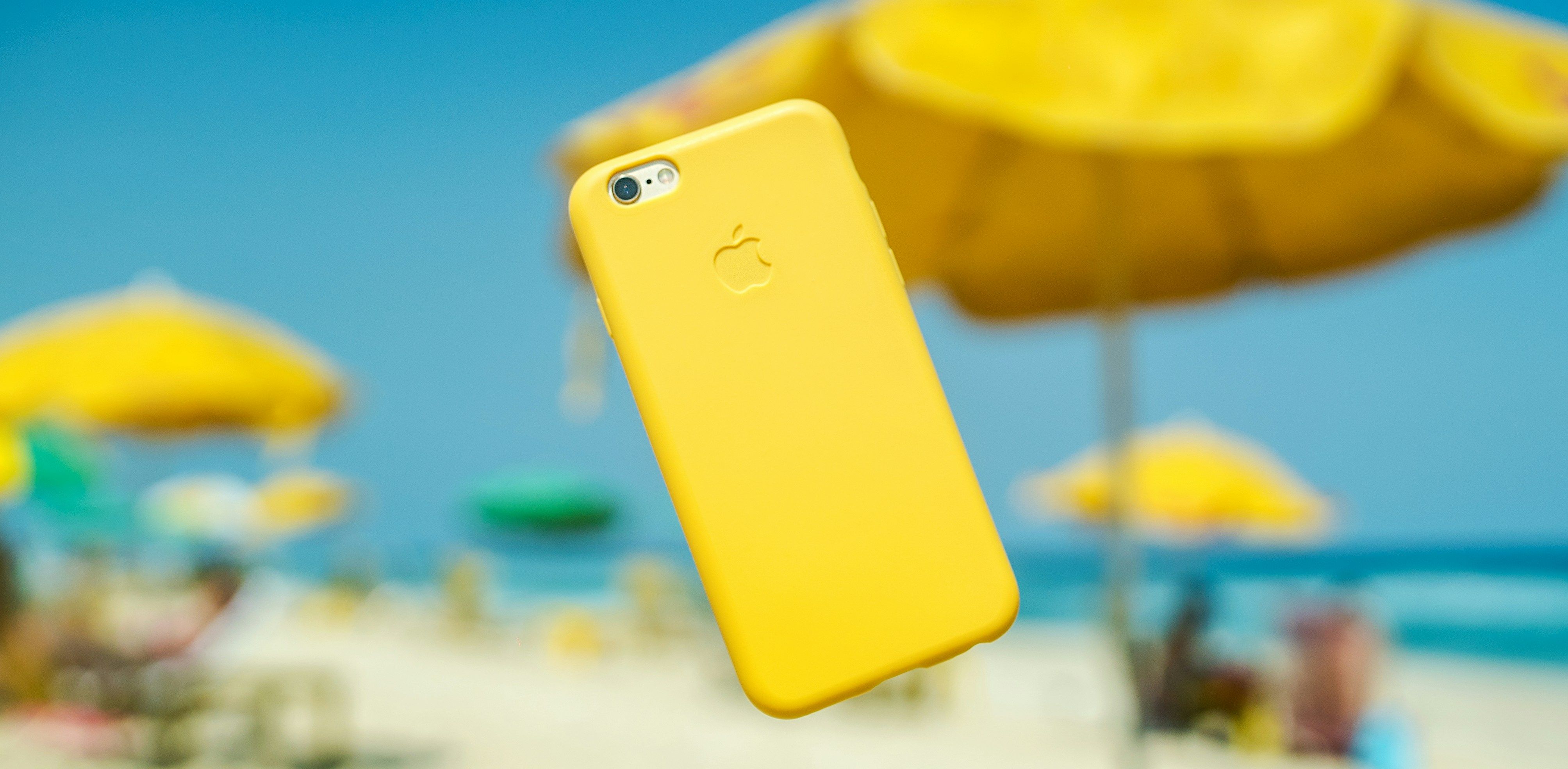 Main Image: iPhone with a yellow cover suspended in the air at Rio beach