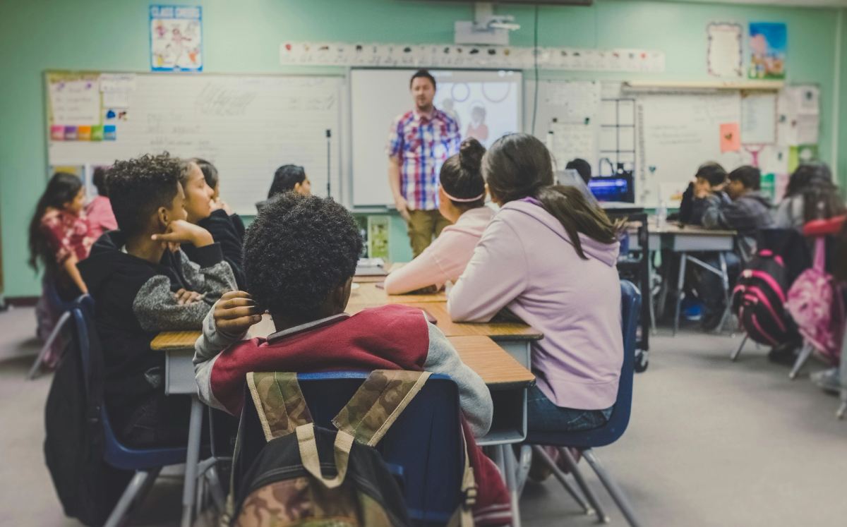 A classroom of students listening to their teacher.
