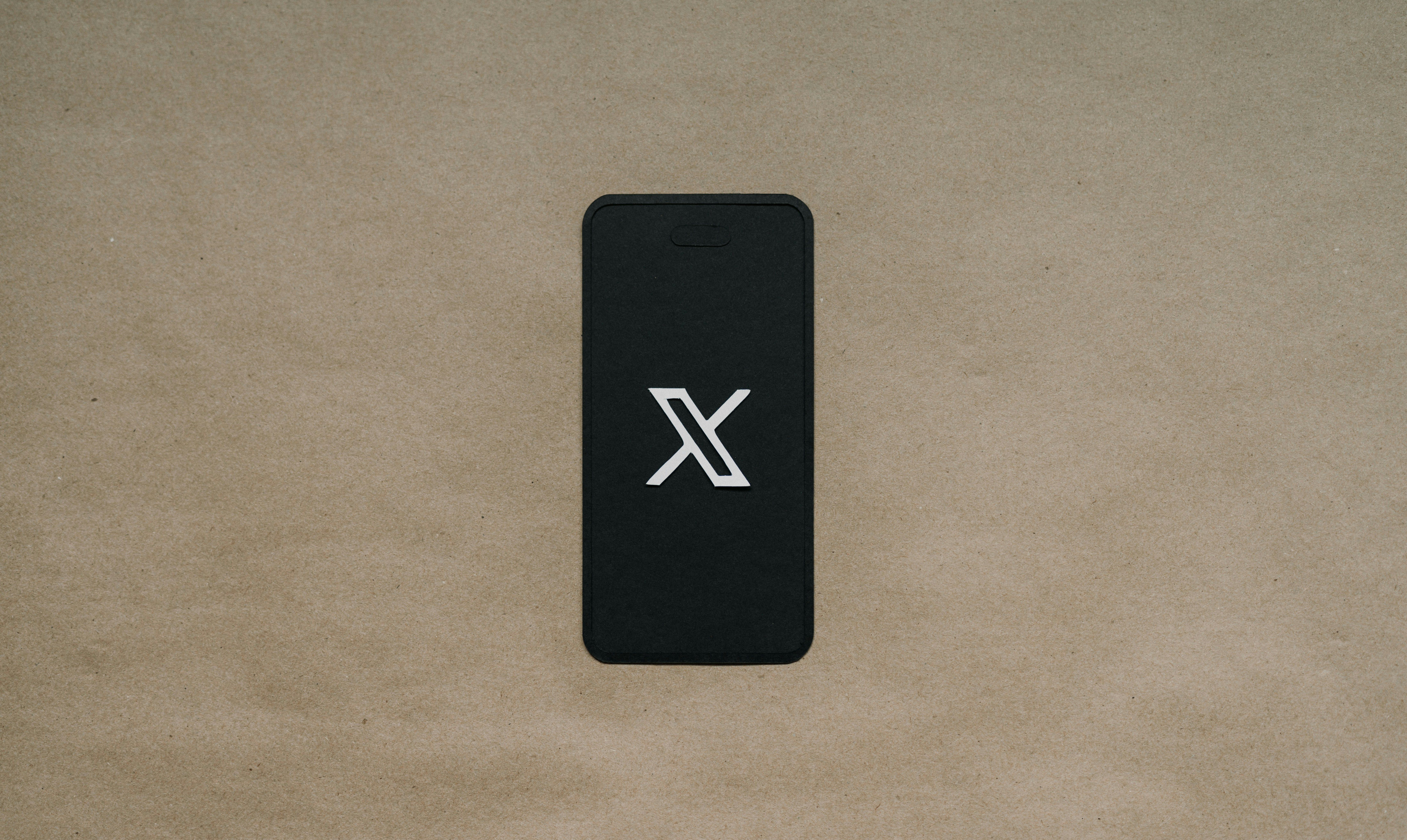 Black mobile phone with X logo on the screen