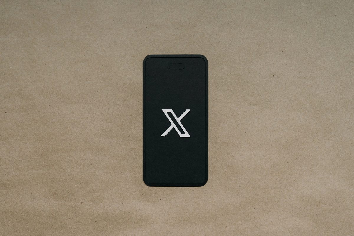 Black mobile phone with X logo on the screen