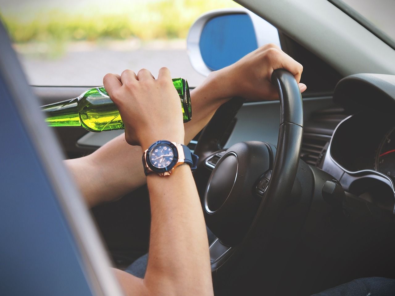 Main Image: A man drinking a beer while driving