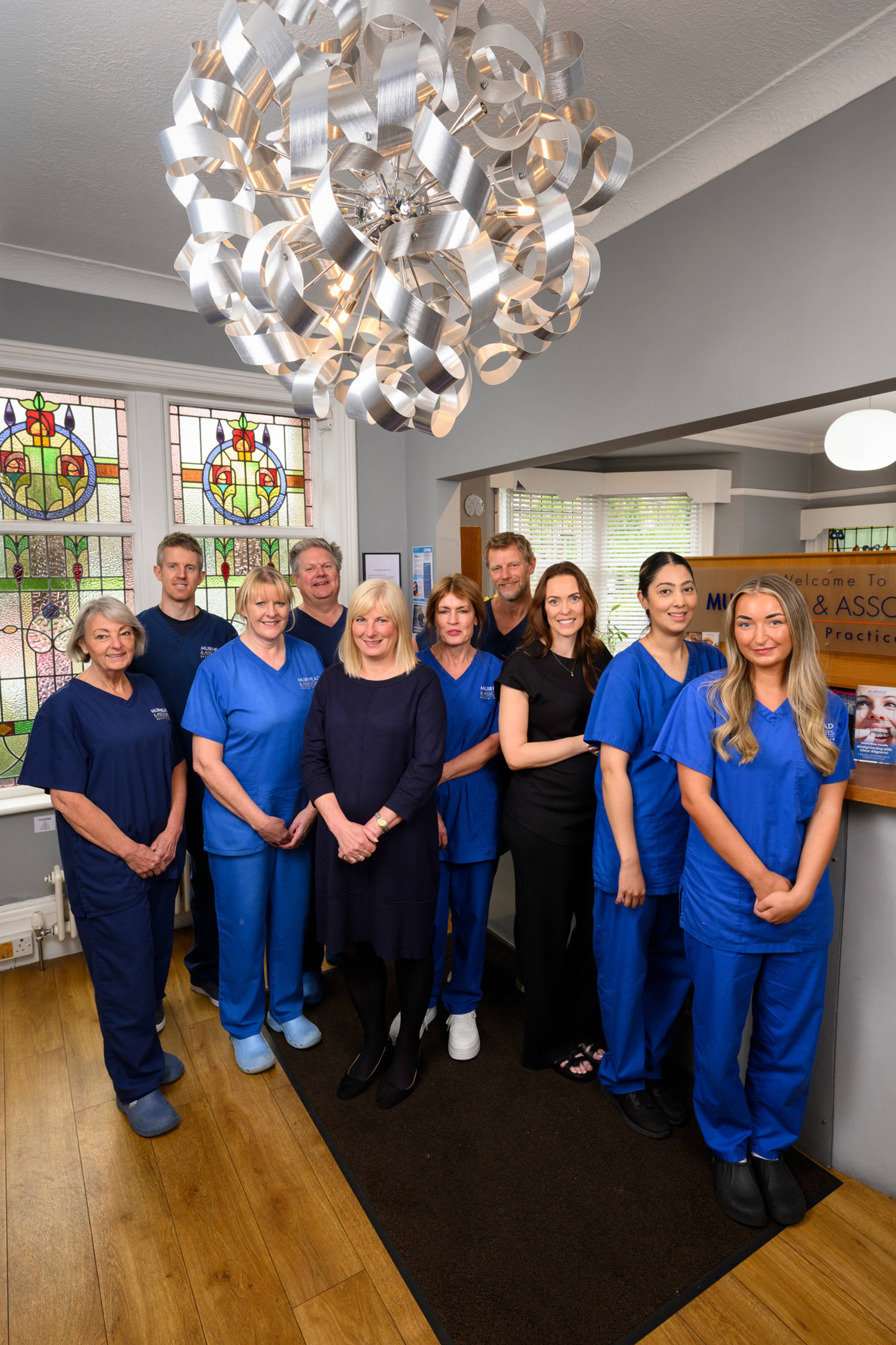 The Muirhead & Associates team standing in the reception area and smiling together
