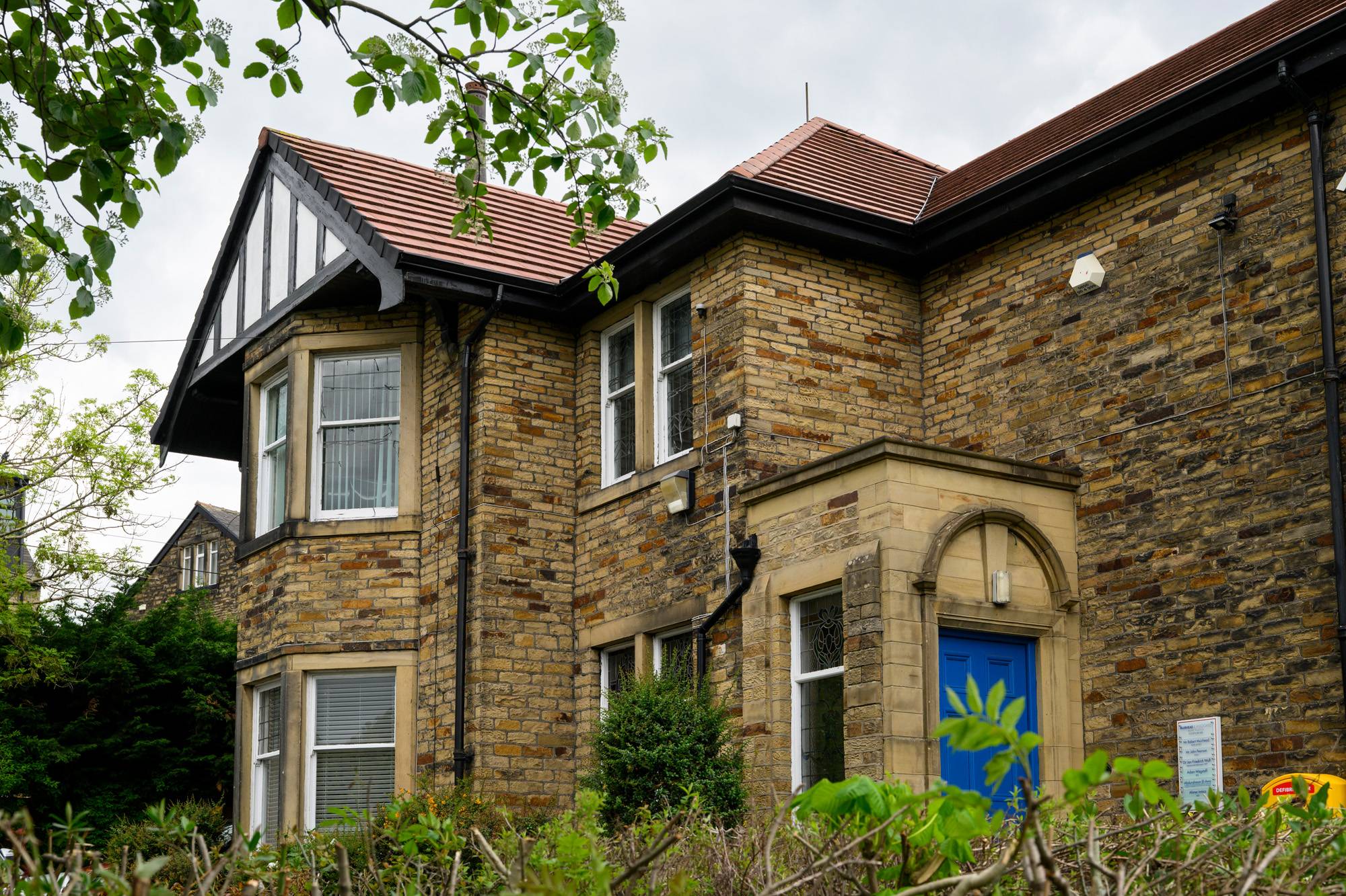 Muirhead & Associates Dental Practice building behind shrubs and a blue door