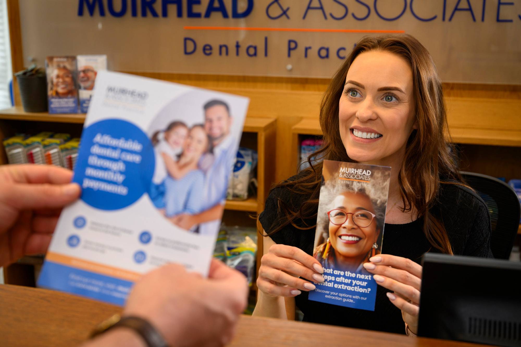 Our receptionist showing a patient one of our membership plan leaflets