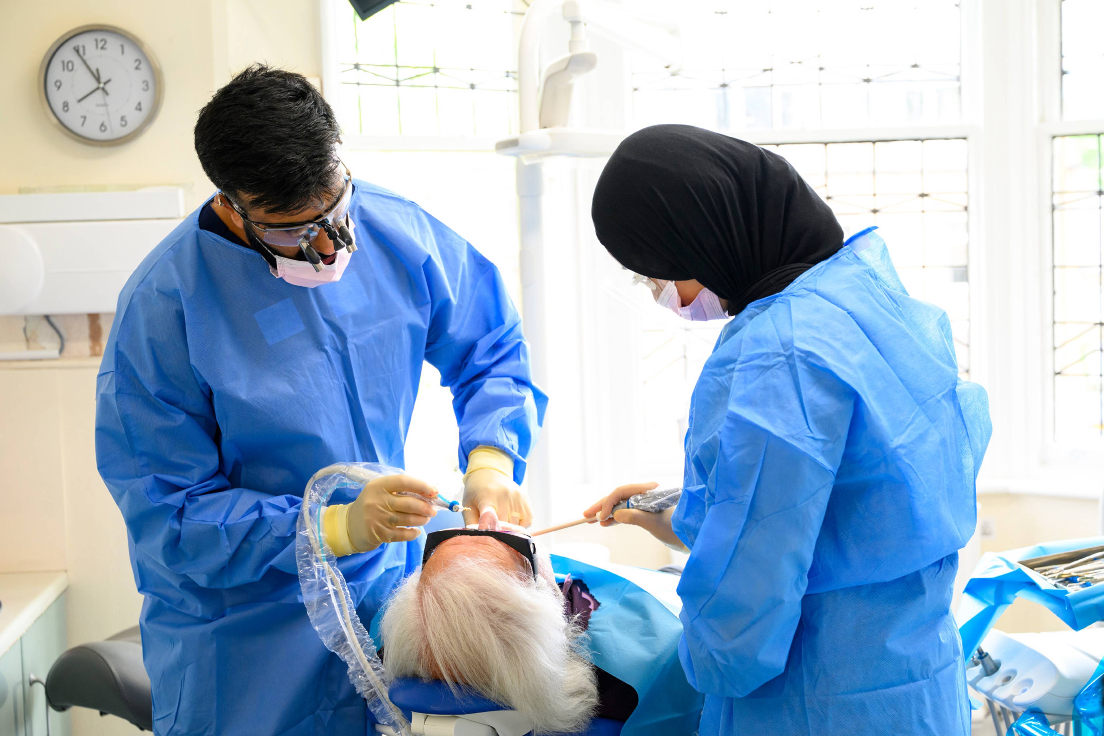 Ahmer and Shifah work on a patient's teeth