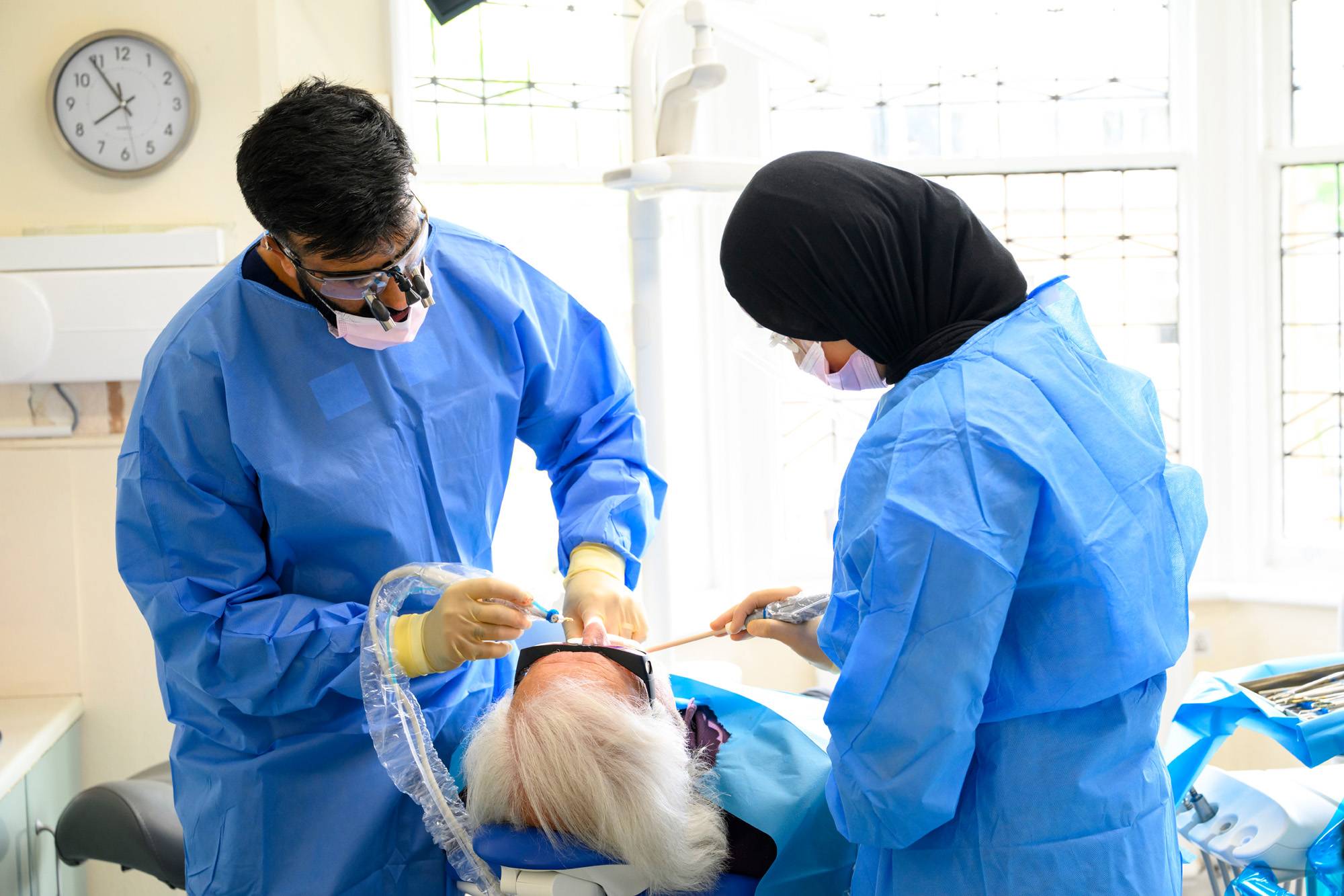 Ahmer and Shifah work on a patient's teeth