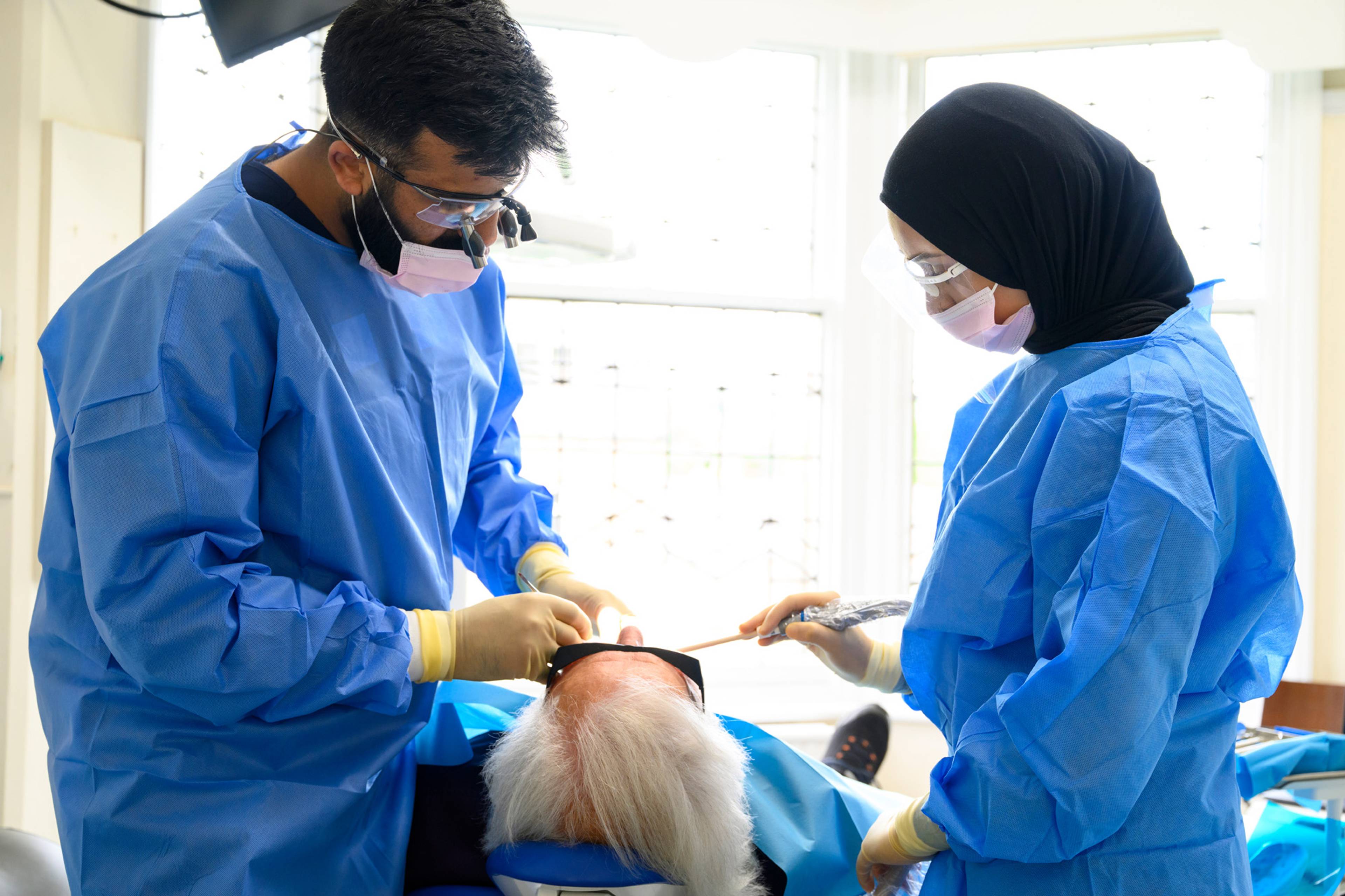 Ahmer and a dental nurse work on a patient together