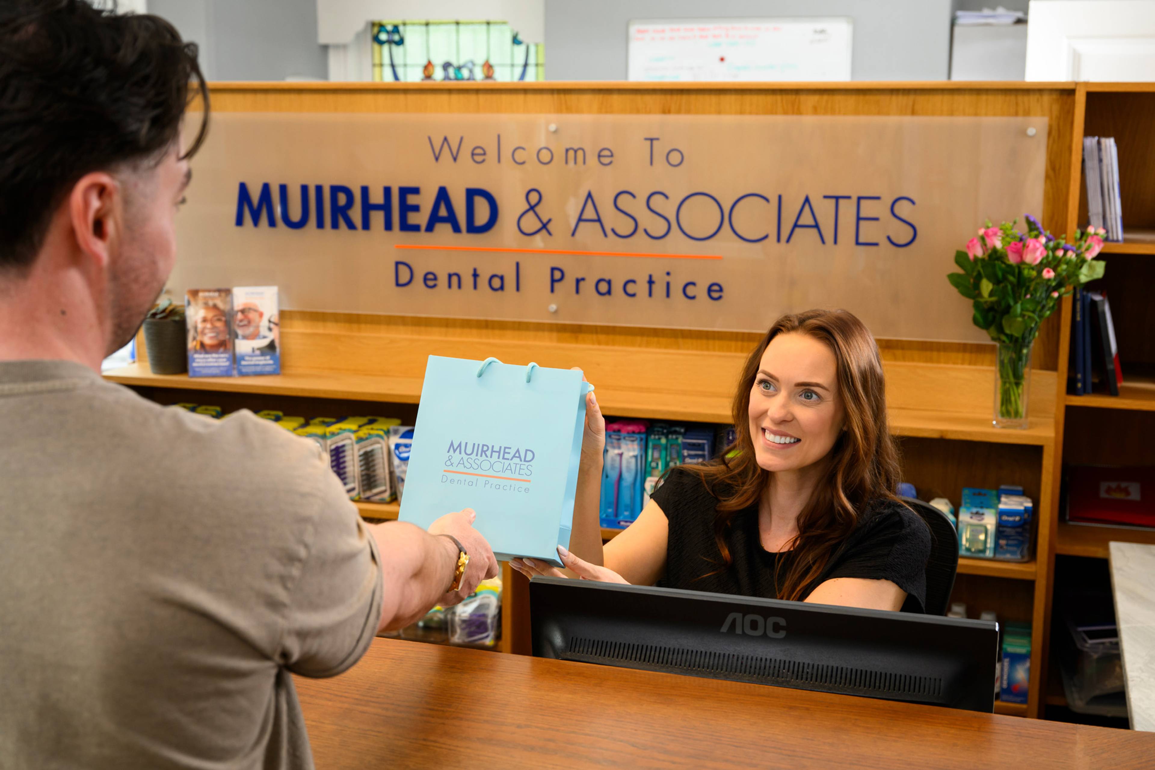Rose Minney hands a branded paper gift bag to a patient