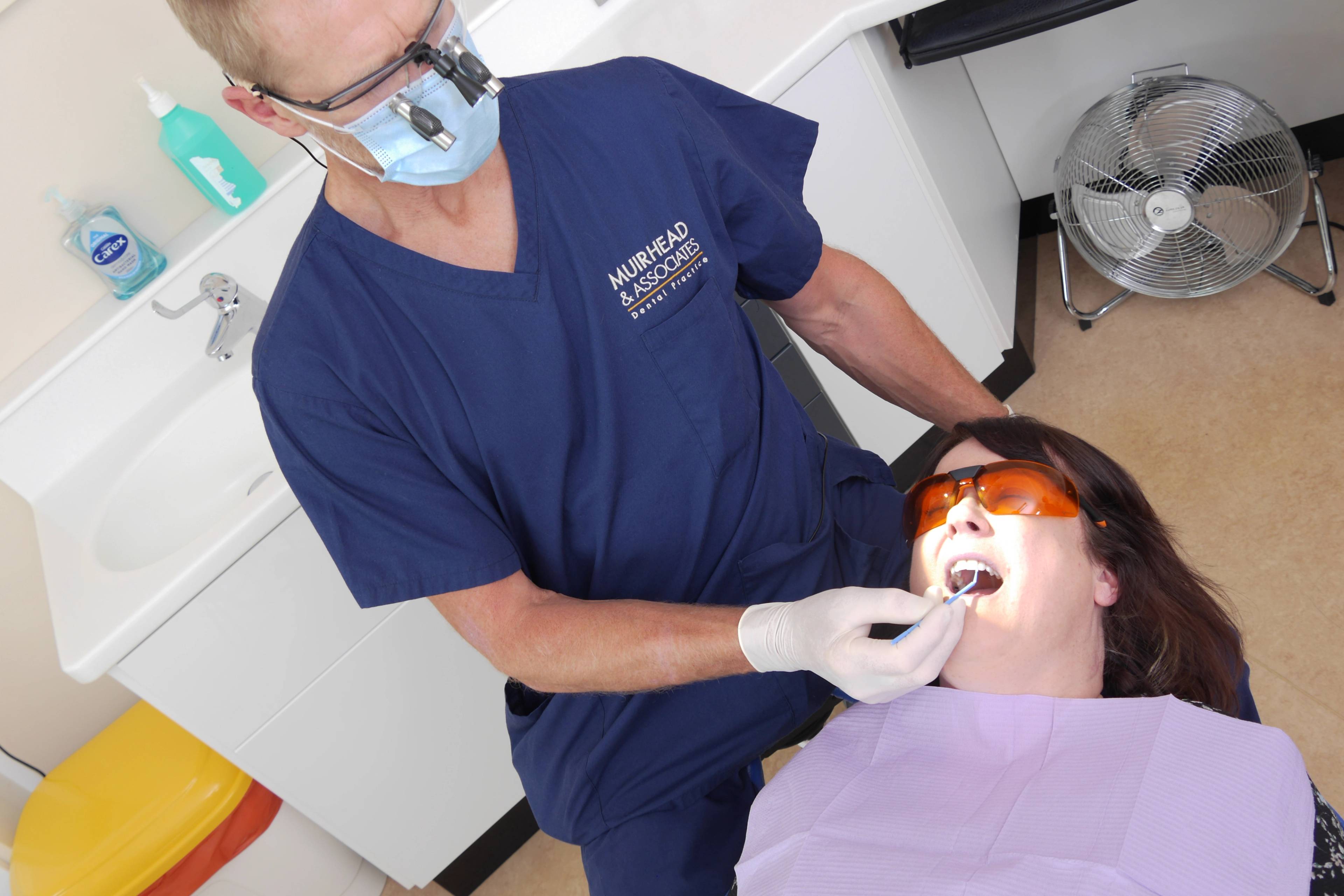 One of our dentists inspects a patient's teeth