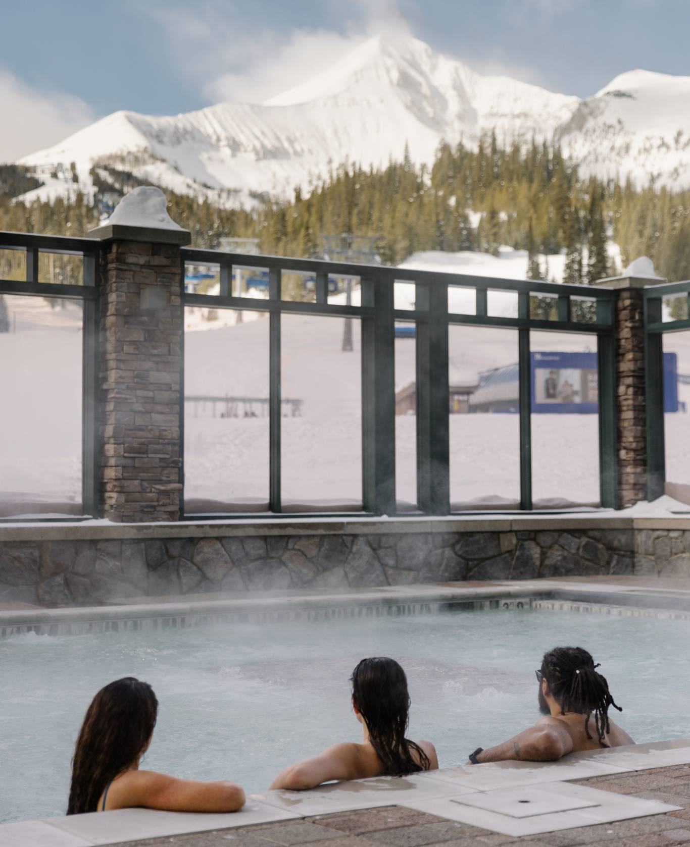 Group of people sitting in a hot tub looking at Lone Mountain in winter