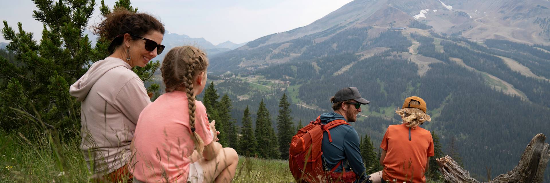 Family sitting in grass with Lone Peak in the background