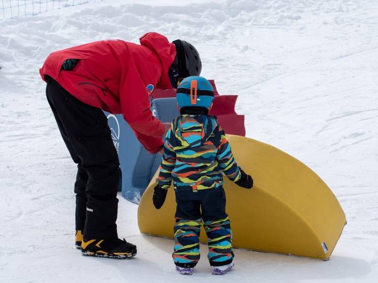 Child in a snowboard lesson with an instructor