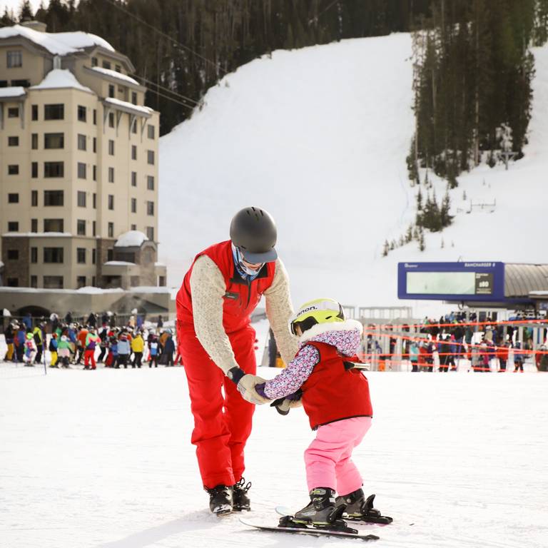 Ski instructor teaching a young girl how to ski