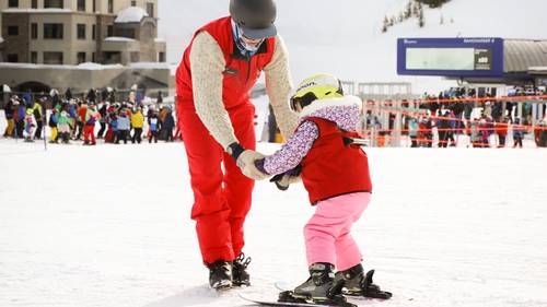 Small child and a ski instructor in a ski lesson