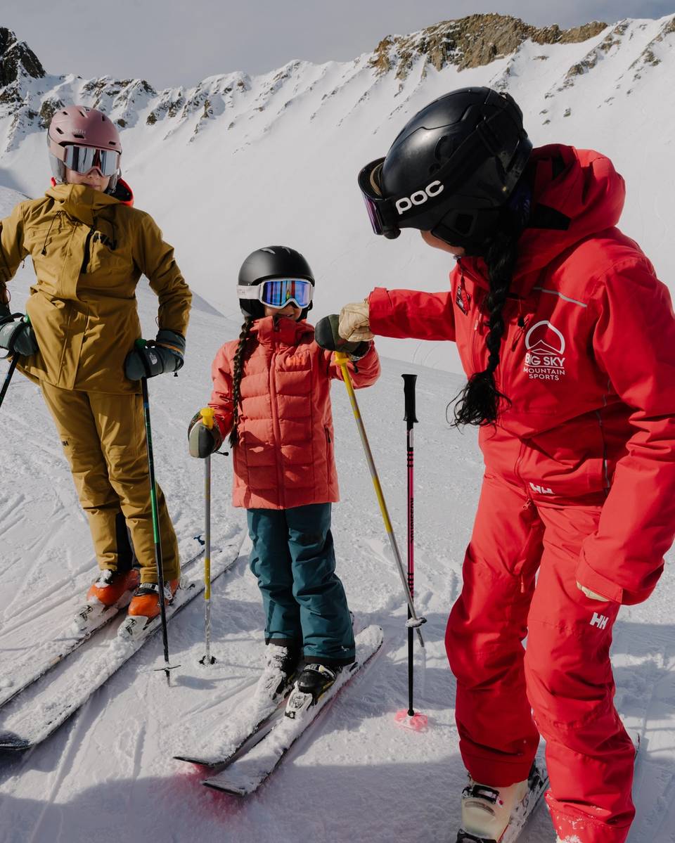 Ski instructor and girl high fiving