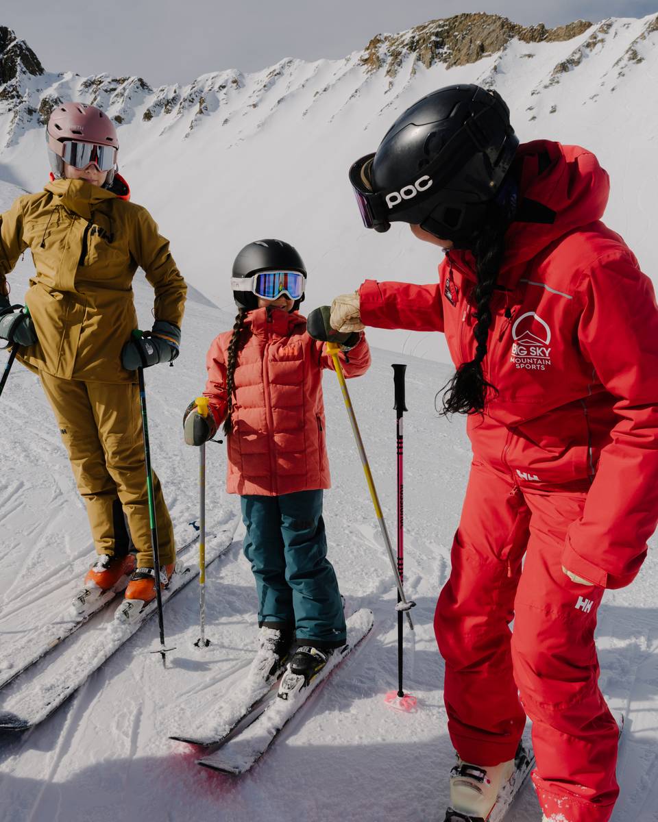 Ski instructor and girl high fiving