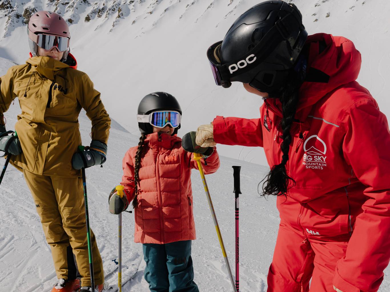Girl and ski instructor fist-bumping in ski gear