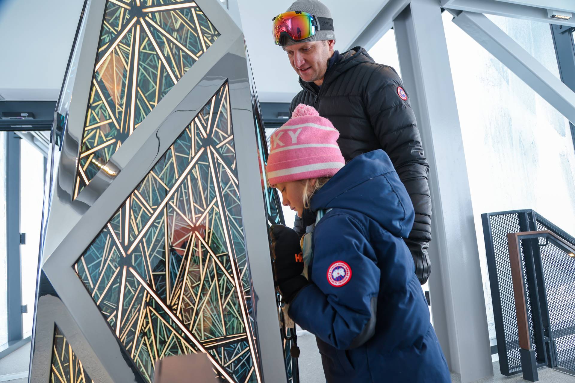 Girl and father looking into a lit art installation