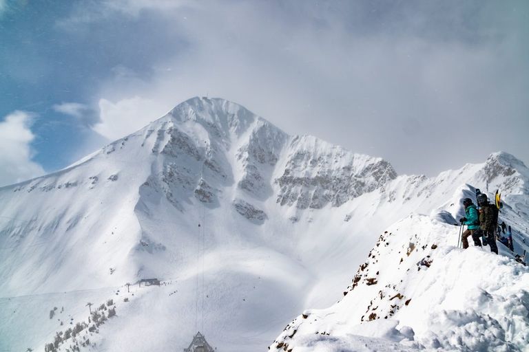 A skier and snowboarder look at lone peak from the Headwaters hike trail