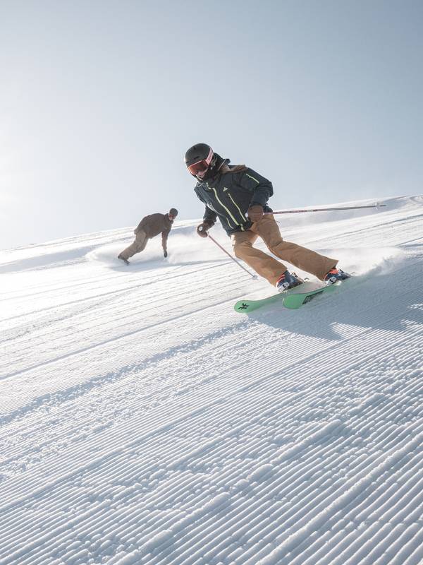 Skier and snowboarder on a groomed run