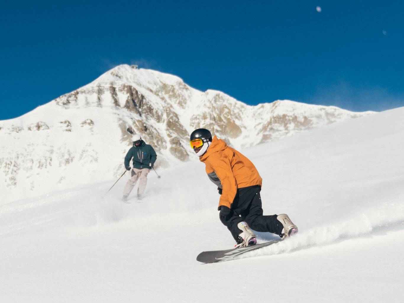 Skier and snowboarder on a groomed run