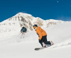 Skier and snowboarder on a groomed run