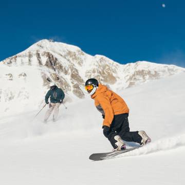 Skier and snowboarder on a groomed run
